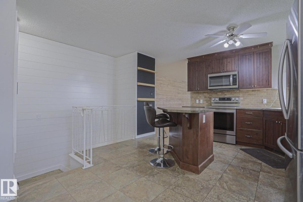 Kitchen area with dark wood cabinets, stainless steel appliances, and a shiplap accent wall. - 53212 Rge Road 14, Rural Parkland County