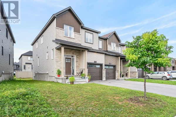 Front view of a townhouse with a covered porch, entryway, and a neighboring unit. - 533 Winterset Road, Ottawa