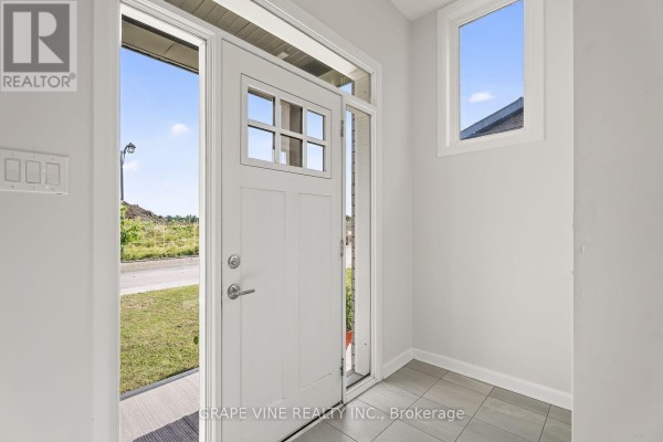 View from inside a townhouse showing the white front door and sidelights with an exterior view. - 533 Winterset Road, Ottawa