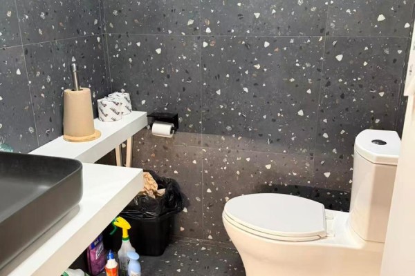 Small bathroom with a toilet, sink, and speckled black tile walls. - 5336 Yonge Street, Toronto