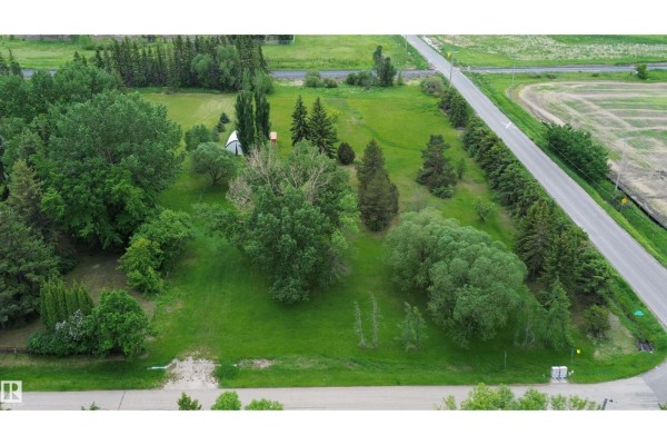 Aerial view showing a treed lot with a white building and a road bordering the property. - 53371 Rge Road 231, Rural Strathcona County
