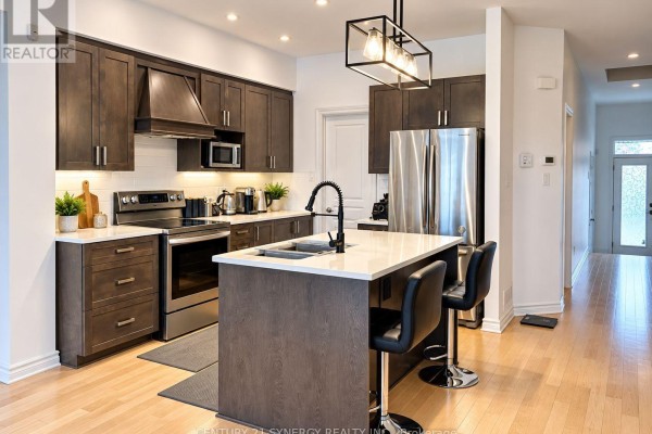 Modern kitchen with dark wood cabinets, stainless steel appliances, and an island. - 534 Grand Tully Way, Ottawa