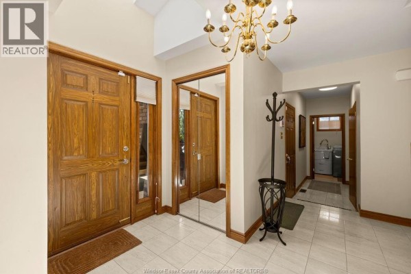 Interior foyer with tiled floors, wooden doors, mirrored closets, and a chandelier. - 534 Michael Crescent, Lasalle