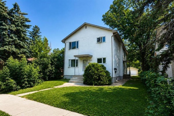 Side view of a white multi-family house with a driveway and garage. - 534 Ritchot Street, Winnipeg