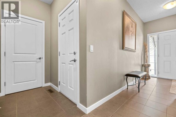 Interior hallway with beige walls, white doors, and a black bench with storage. - 534 River Heights Crescent, Cochrane
