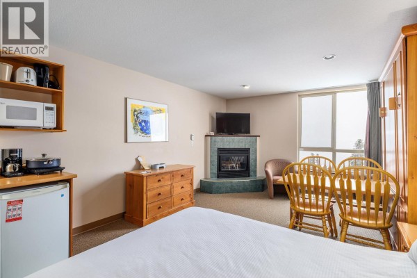 Studio apartment featuring a kitchenette, fireplace, and seating area with a view. - 5340 Big White Road Unit# 220, Big White