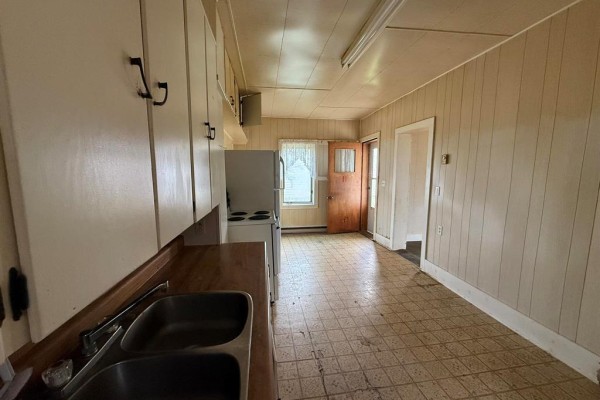 Storage room with shelves, a vacuum cleaner, a box, and fishing gear against yellow walls. - 535 Curwen Street, Cartwright