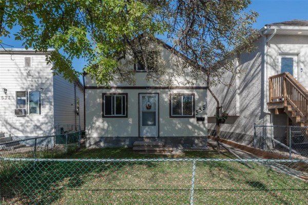 Front exterior view of a light-colored, two-story house with a covered entrance and a fenced lawn. - 535 Jamison Avenue, Winnipeg