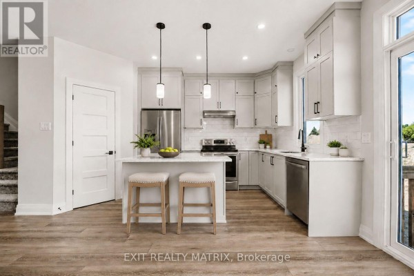 Kitchen with light grey cabinets, stainless steel appliances, island with stools, and pendant lights. - 535 Regina Street, Russell