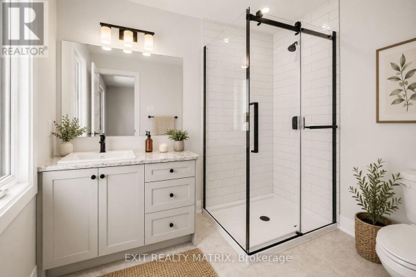 Bathroom with double vanity, white subway tile shower with glass doors, and toilet. - 535 Regina Street, Russell