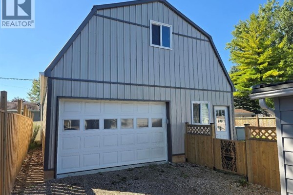 Gray barn-style garage with a large white overhead door and a side door. - 535 Richmond Street, Dresden
