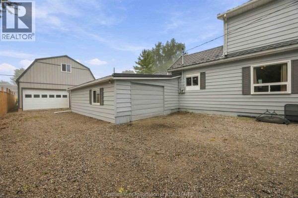 Gravel driveway and yard with a two-story house and garages in the background. - 535 Richmond Street, Dresden