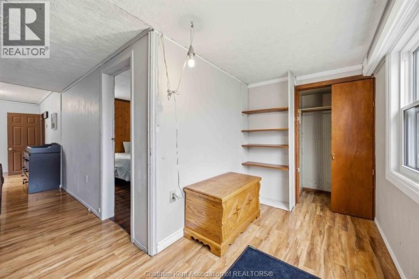 Interior room with wooden floor, open shelves, wooden chest, and closet with sliding doors. - 535 Richmond Street, Dresden