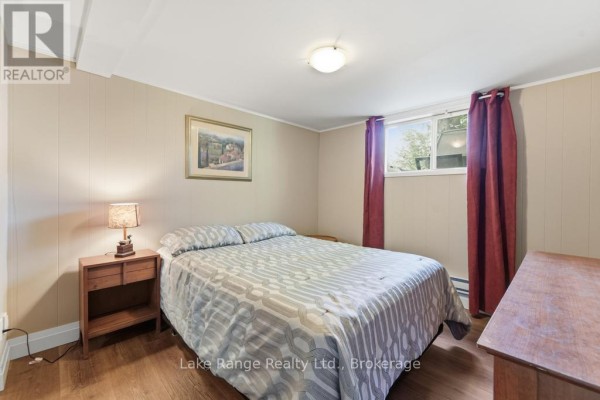 Bedroom with patterned bedding, nightstand, and window - 536 Alfred Street Huron Kinloss