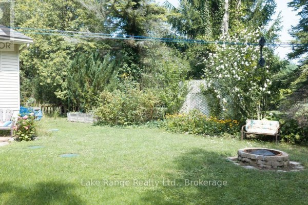 Backyard with fire pit, lawn chairs, bench, and lush landscaping - 536 Alfred Street Huron Kinloss