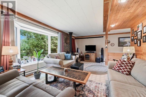Living room with bay window, wood stove, and wood paneling - 536 Alfred Street Huron Kinloss