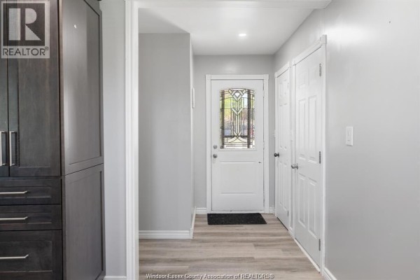 Interior hallway with grey walls, white doors, a decorative glass front door, and wood-look flooring. - 536 Mersea Rd 3, Leamington