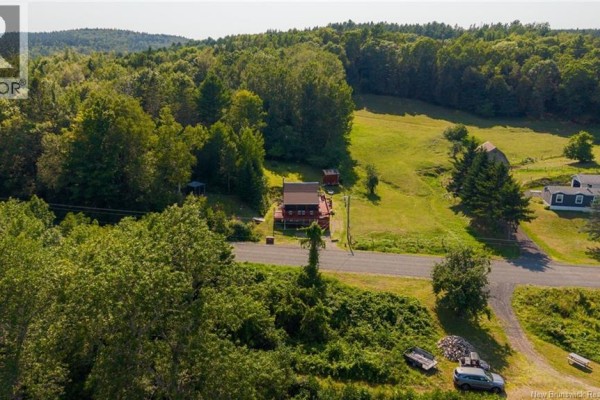 Aerial view of the cottage and surrounding rural landscape with rolling hills and trees. - 5364 Route 102, Hampstead
