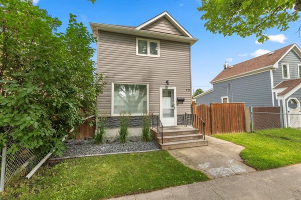 Front view of a two-story grey house with a wooden fence. - 537 Cherrier Street, Winnipeg