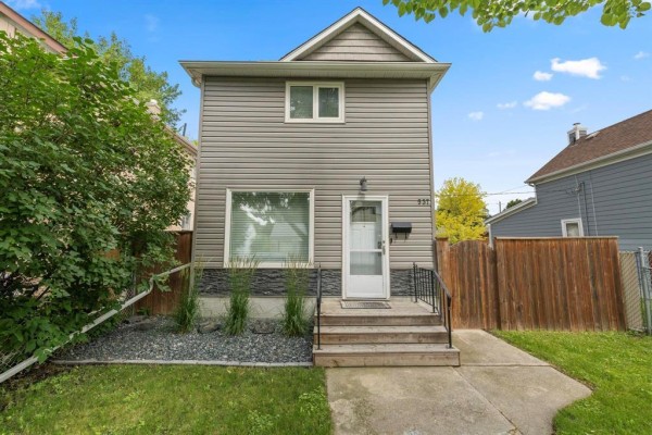 Grey siding house exterior with a small porch and a driveway. - 537 Cherrier Street, Winnipeg