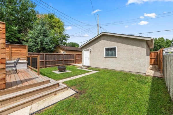 Backyard with a wooden deck, hot tub, fire pit, and a garage. - 537 Cherrier Street, Winnipeg