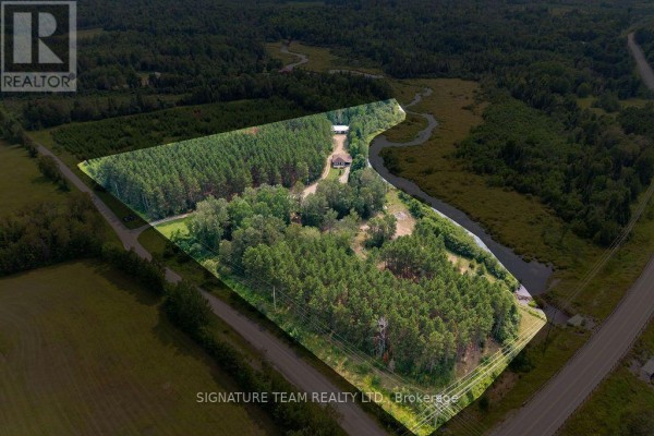 Aerial drone shot highlighting the property at 538 Lenser Road, Bonnechere Valley, surrounded by dense forest and a winding creek. - 538 Lenser Road, Bonnechere Valley