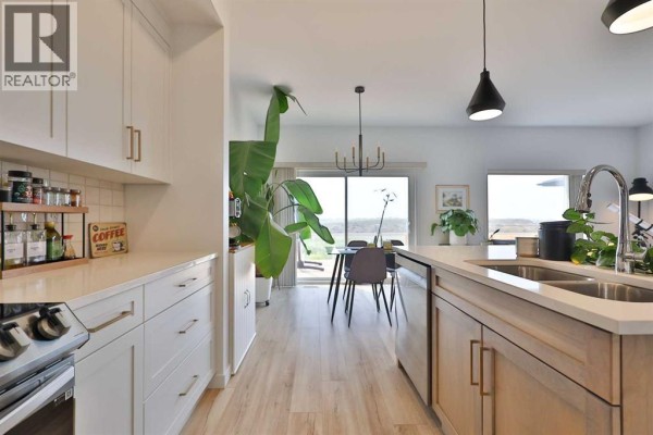 View from the kitchen island looking towards the dining area and a large window. - 538 Malahat Green W, Lethbridge