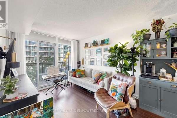 Living room with light grey sofa, leather armchair, digital piano, and large window. - 539 - 8 Telegram Mews, Toronto