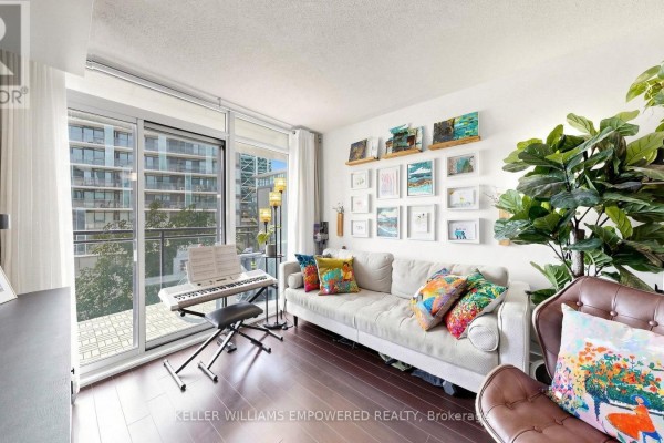 Living room with sectional sofa, decorative wall art, digital piano, and floor-to-ceiling window. - 539 - 8 Telegram Mews, Toronto