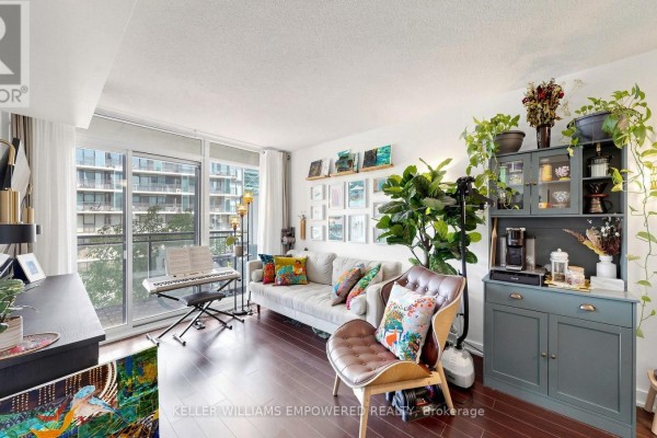 Living room with sectional sofa, dark green cabinet, digital piano, and balcony view. - 539 - 8 Telegram Mews, Toronto