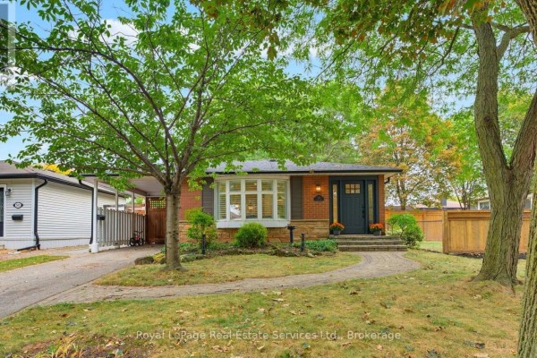 View of the bungalow's brick exterior, landscaped front yard, and driveway with carport. - 539 Galway Drive, Burlington