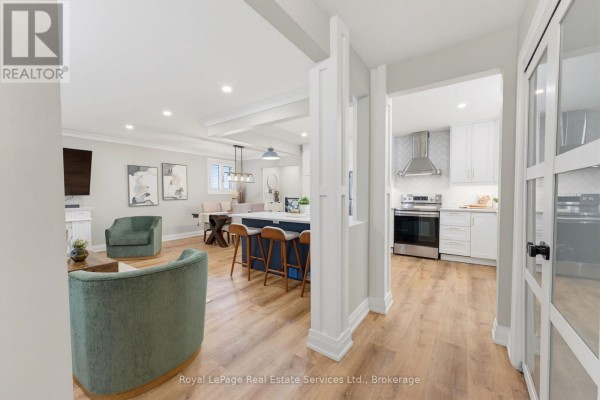 Open-concept living, dining, and kitchen area with island, modern furniture, and stainless steel appliances. - 539 Galway Drive, Burlington