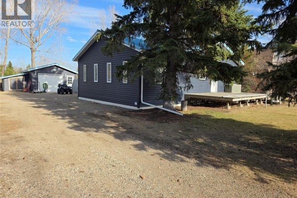 Dark blue vinyl sided house with a detached garage, an ATV, and a gravel driveway. - 539 Mistusinne Crescent, Mistusinne