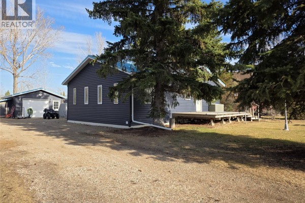 Dark blue vinyl sided house with a detached garage, an ATV, and a gravel driveway. - 539 Mistusinne Crescent, Mistusinne
