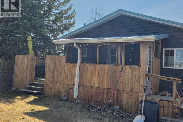 Wooden screened-in porch with wooden stairs and railings attached to the dark blue vinyl sided house. - 539 Mistusinne Crescent, Mistusinne