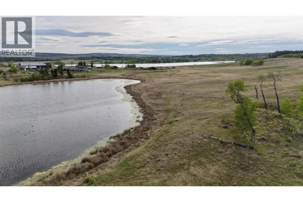 Close-up of the lake's edge with frozen surface and surrounding grassland. - 5391 Tatton Station Road, 100 Mile House