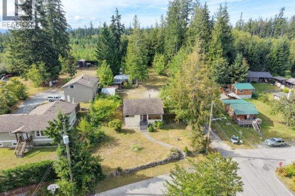 Aerial view of the residential property surrounded by other homes and dense evergreen trees. - 5392 Dale Ave, Powell River