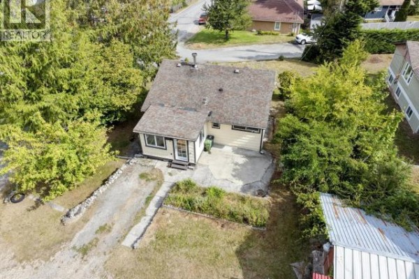 Aerial view of the rear exterior of the bungalow, showing a patio and driveway. - 5392 Dale Ave, Powell River