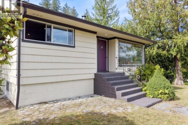 Close-up of the front entrance with dark steps, a purple door, and large front window. - 5392 Dale Ave, Powell River
