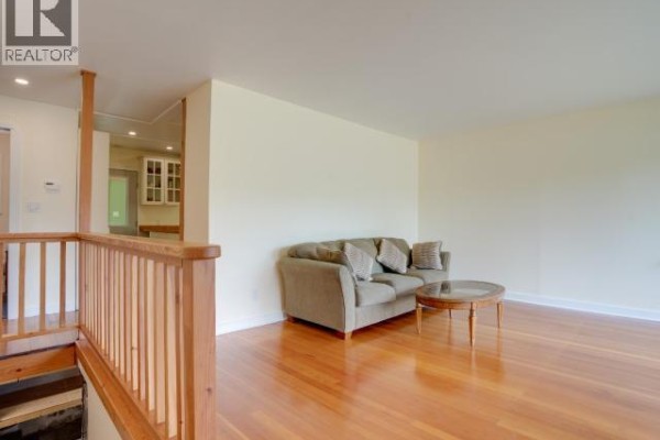 Living room with a beige sofa, round coffee table, hardwood floors, and light yellow walls. - 5392 Dale Ave, Powell River
