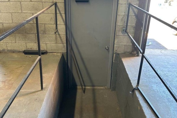 Gray metal door with handrails on concrete steps leading down. - 54 - 173 Advance Boulevard, Brampton