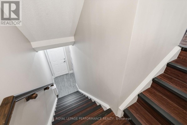Interior view looking down a wooden staircase with white walls and a gray tiled floor below. - B - 285 Titanium Private, Ottawa