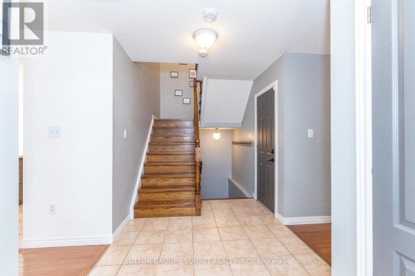 Tiled foyer with a wooden staircase leading upstairs and a view of the hallway. - 54 - 4055 Forest Run Avenue S, Burlington