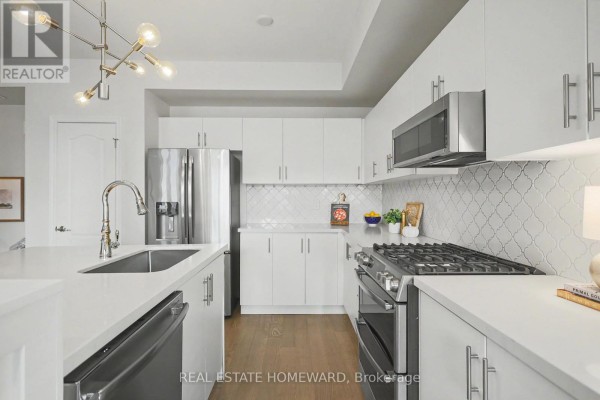 Modern kitchen with white cabinets, stainless steel appliances, and an island. - 54 - 57 Armdale Road, Mississauga
