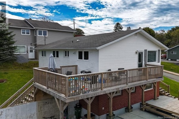 Rear exterior of a white house with a large wooden deck overlooking a grassy yard. - 54-56 Northumberland Avenue, Saint John