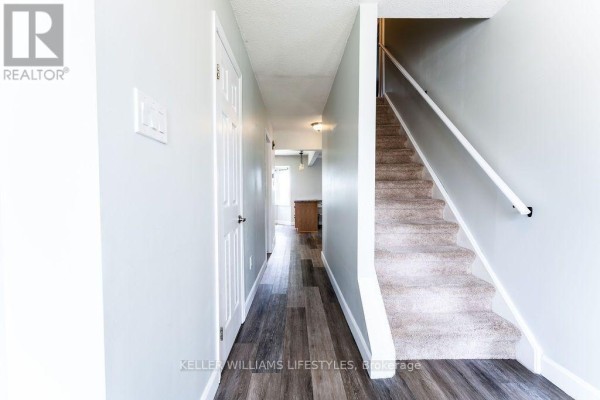 Hallway with a staircase to the right, white doors, and dark wood laminate flooring. - 54 Bexhill Drive, London South