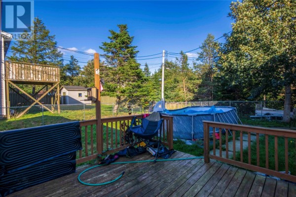 Wooden deck overlooking a grassy backyard with an above-ground pool and mature trees. - 54 Cherrigton Street, St  John S