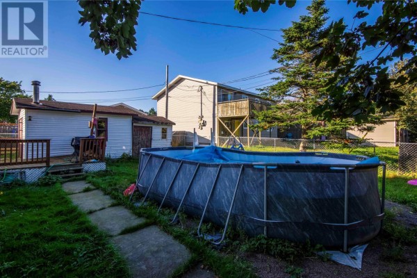 Rear view of a house with a large above-ground pool and a wooden deck in the backyard. - 54 Cherrigton Street, St  John S