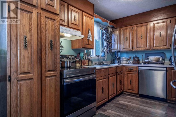 Kitchen with light oak cabinets, stainless steel appliances including a gas range, and grey wood-look flooring. - 54 Cherrigton Street, St  John S