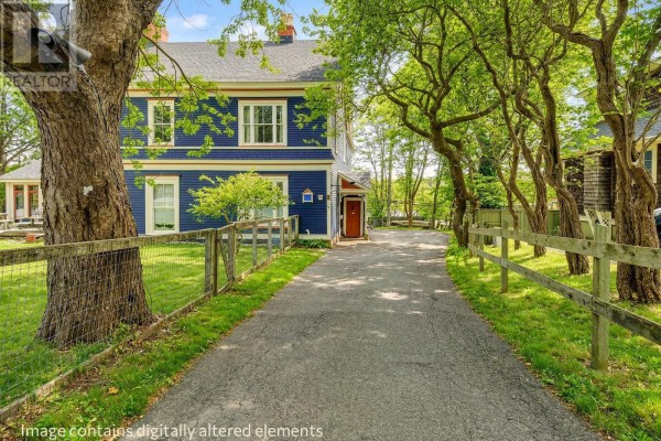 Front exterior view of blue house with white trim, green lawn, and trees. - 54 Circular Road, St  John S